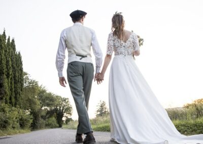 Les mariés de dos marchent sur la route